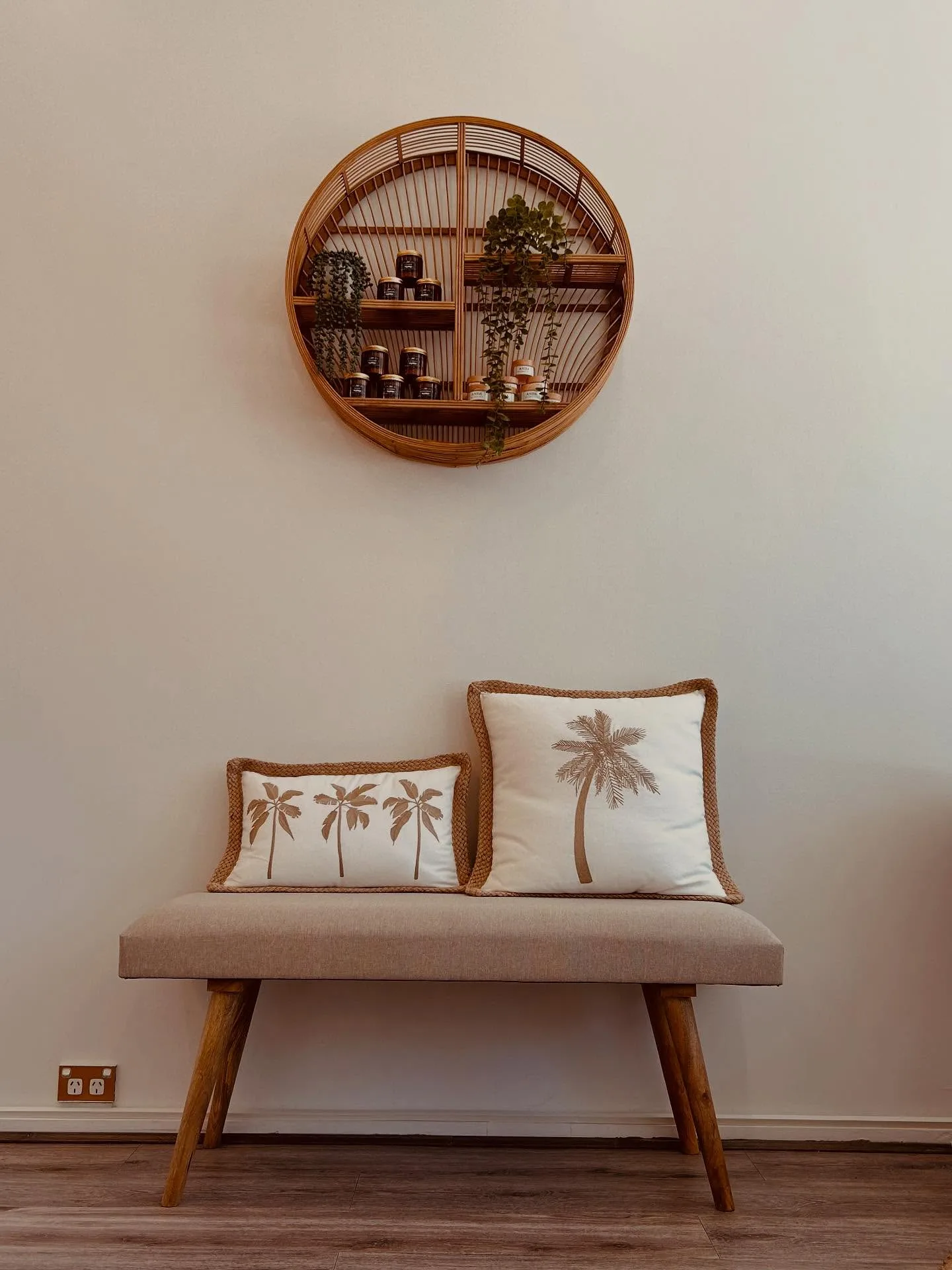 Round rattan wall shelf with ANDA product jars and trailing plants