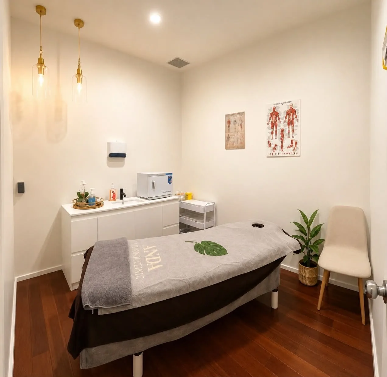 Bright white treatment room with warm timber floor, twin pendants and potted palm — Camberwell